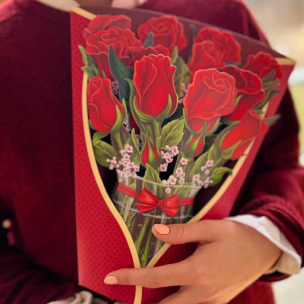 image of paper bouquet opened, featuring large red roses, small light pink blossoms, in a glass looking vase.  Small greeting card with red rose in the right forefront