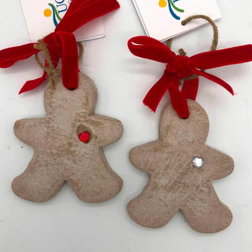 image of two gingerbread style ornaments, one with a red gem heart and one with a clear gem heart, both with red ribbon hangers