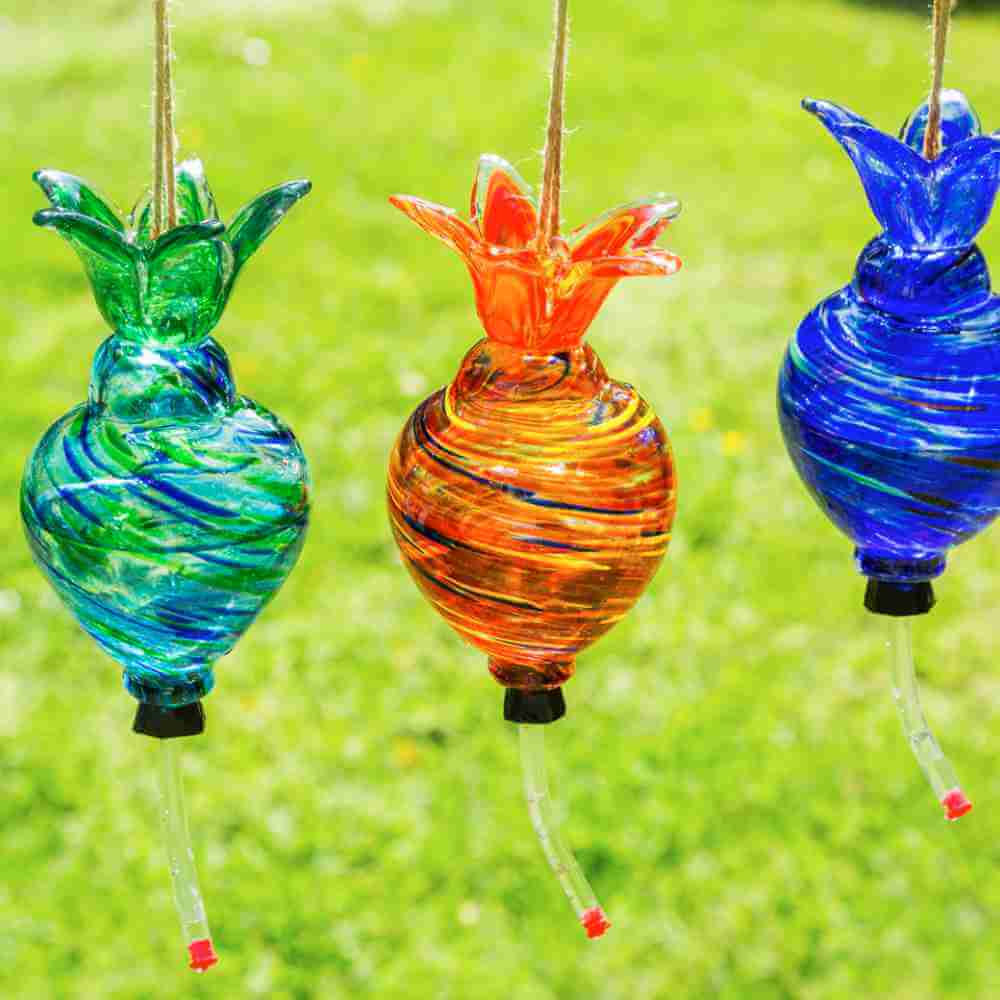 image of three hanging glass hummingbird feeders in aqua, orange and blue