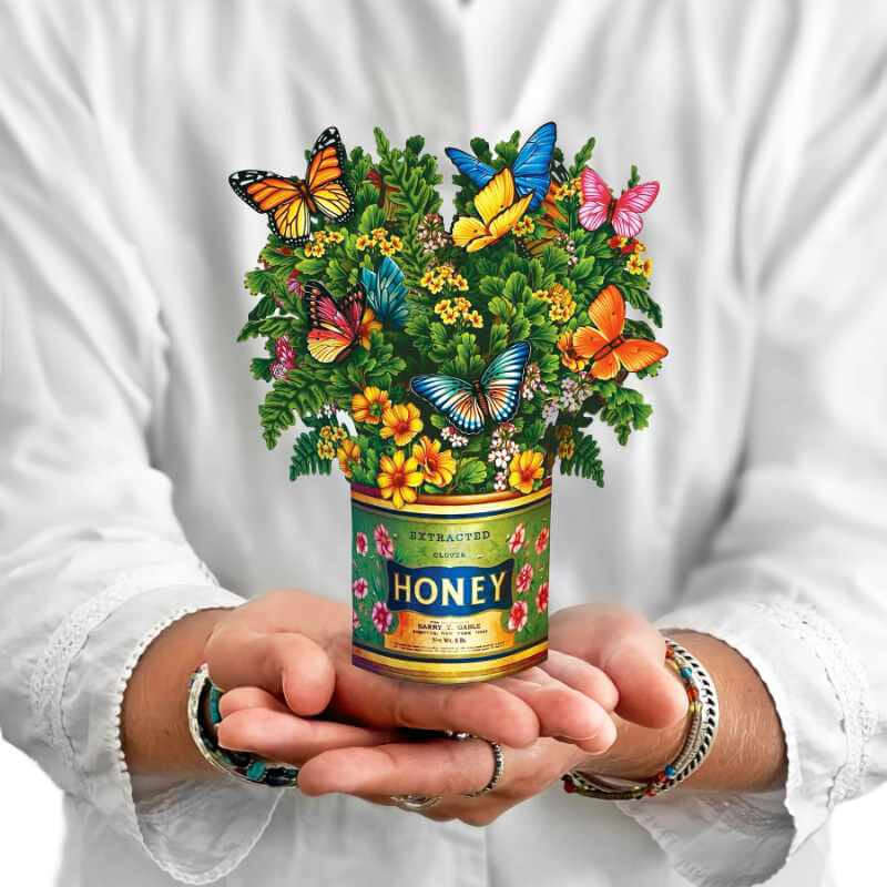 image of person in white holding a paper bouquet in a honey jar looking vase holding multiple wild flowers with different color butterflies