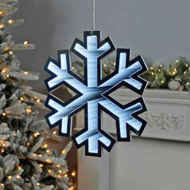 Decorative LED snowflake hanging in a festive setting with Christmas tree and lights.