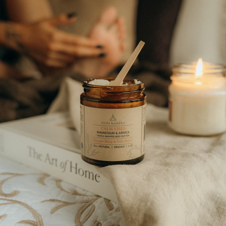 Jar of 'Calm Vibes' product on a surface with a candle and book in the background