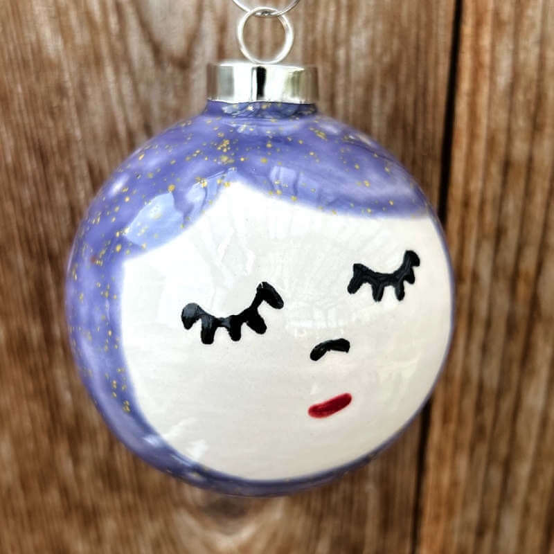 Decorative ceramic ornament with a face design sitting on a wooden background