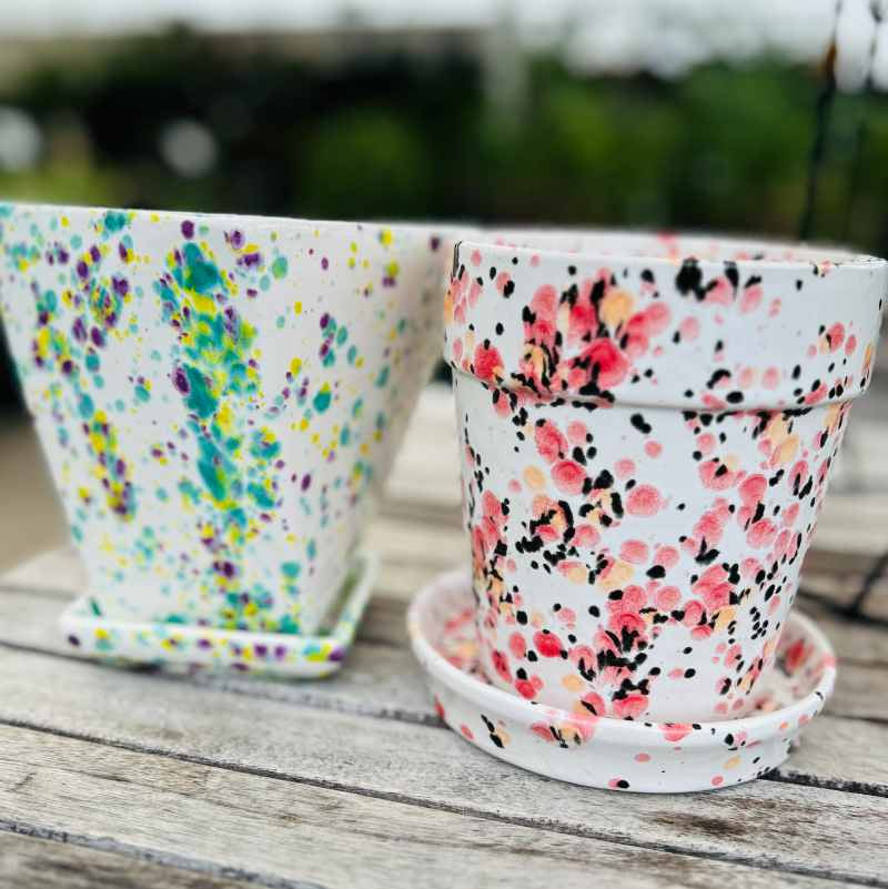 Two colorful spotted ceramic pots on a wooden surface 