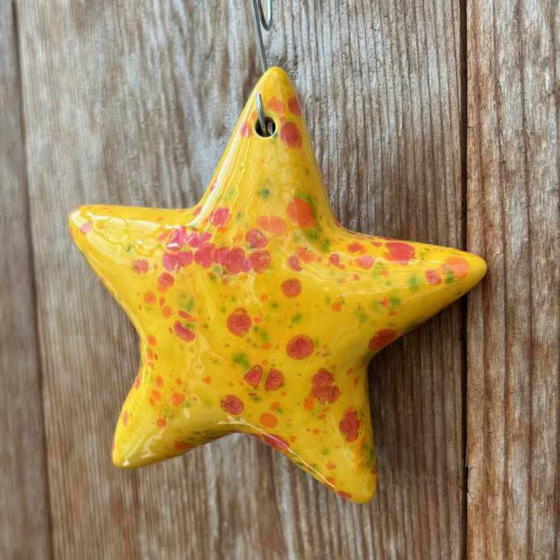 Yellow star-shaped ornament with speckled pattern on a wooden surface