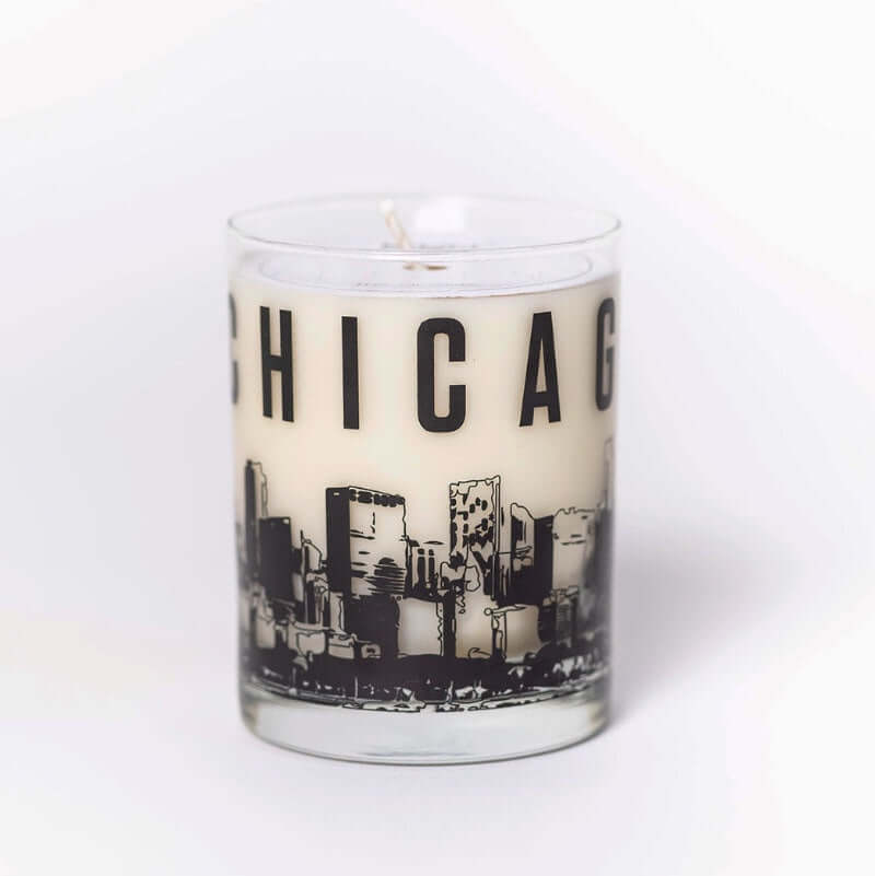 image of white candle in clear glass jar with chicago printed along the top and a drawing of chicago's skyline along the bottom
