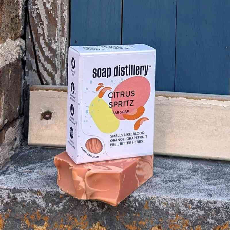 image of white soap box with yellow and peach circular designs sitting on a bar of soap in shapes of cream and dusty pink