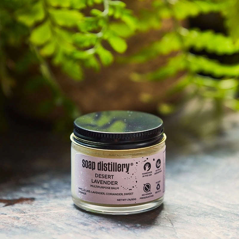 image of round glass jar with black lid with light lavender color label