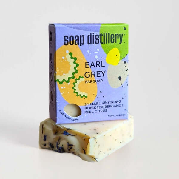 box of soap in bright tones of periwinkle, lime green yellow and gold with soap distillery logo and soap information