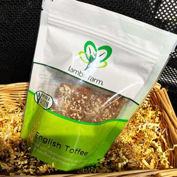 mage of pieces of english toffee topped with crushed pecans.  Box with label in background