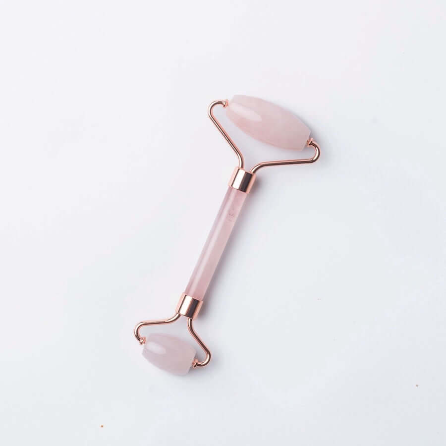 image of rose quartz roller with thin center and two different size quartz rollers at each end held by brass wires