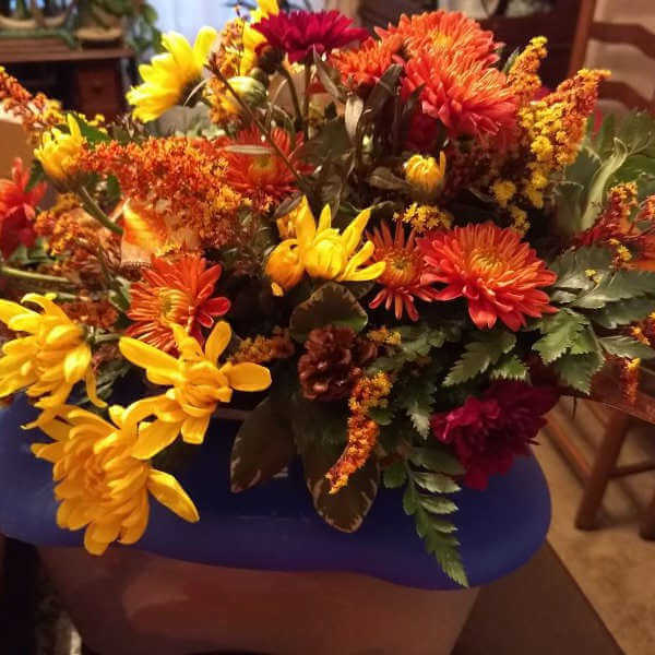 closeup image of a flower arrangement with different types of flowers in yellow, green, gold and deep orange red