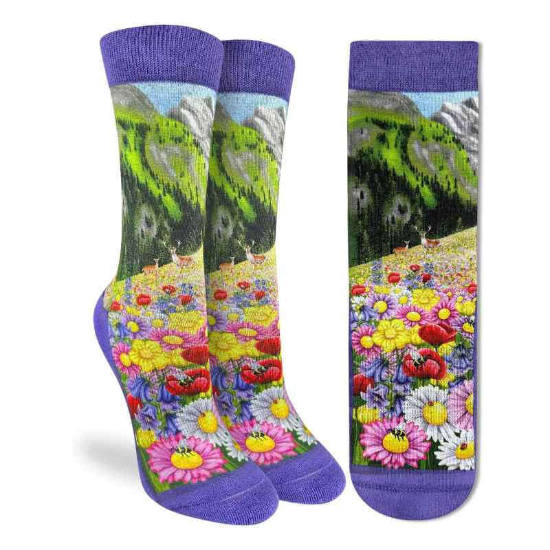 image of a pair of socks in purple with drawings of a meadow full of different colored flowers against a backdrop of mountains