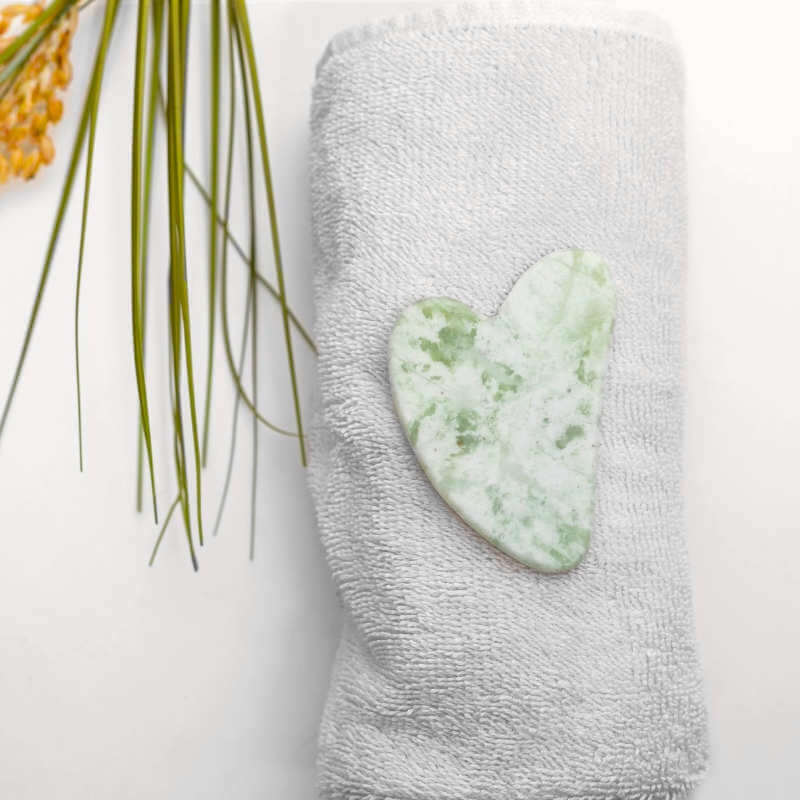 image of heart shaped white and jade colored flat stone sitting on a white towel