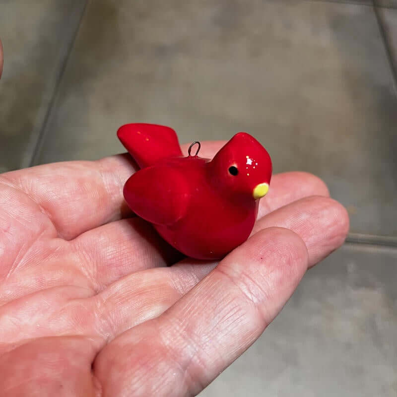 image of hand holding a tiny red ceramic cardinal bird ornament
