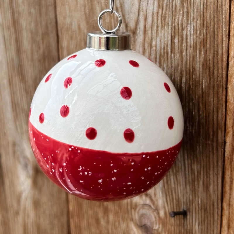 Decorative Christmas ball ornament with red polka dots and red base on a wooden background