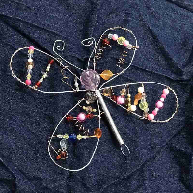 image of a wire whisk bent into the shape of a butterfly and covered with twirling wires and multi colored beads