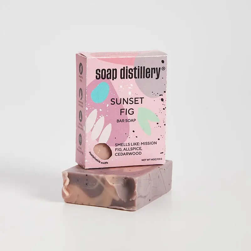image of soap box in pink with rounded designs in grey blue and light green sitting on a bar of soap in a swirled mauve and peach tone