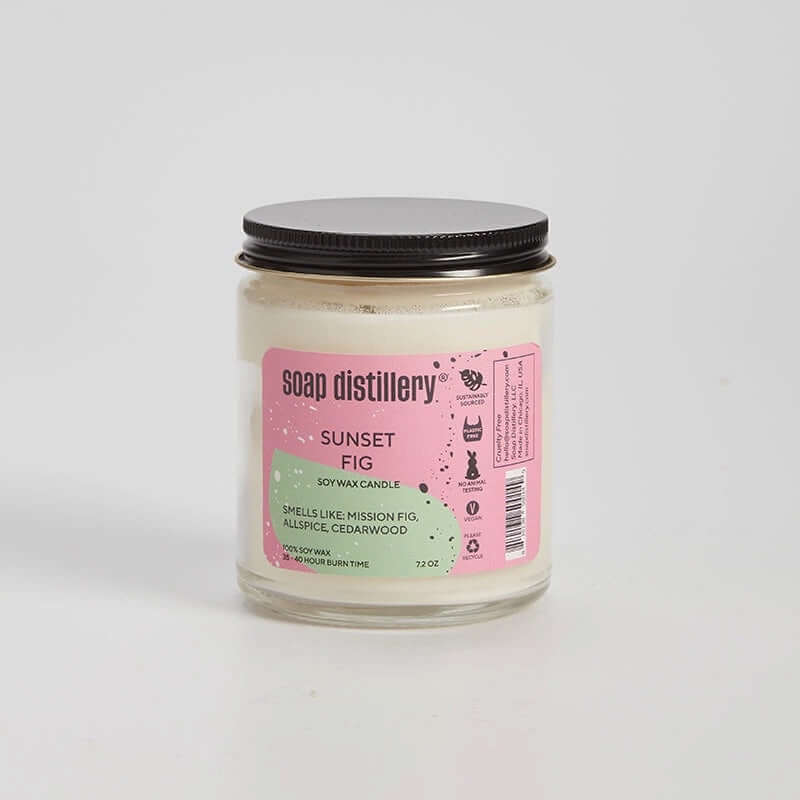 image of candle in clear glass jar with black lid and label in pink and pale green