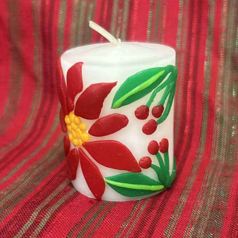 Decorative candle with red floral design on a red fabric background