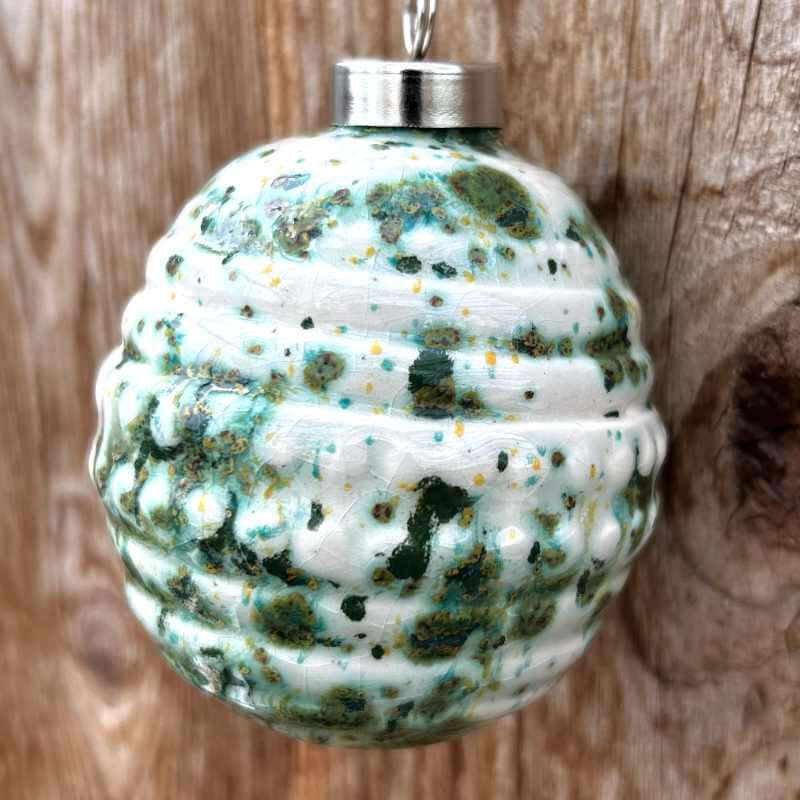 Speckled ceramic ornament with a silver top on a wooden background