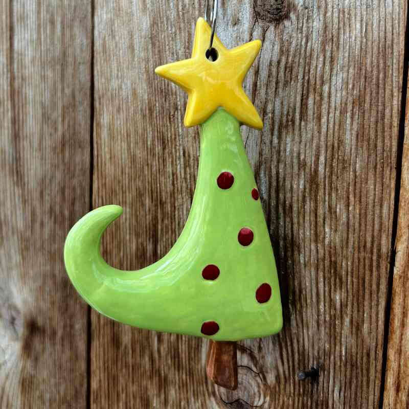 Whimsical ceramic tree with red dots and yellow star on a wooden background