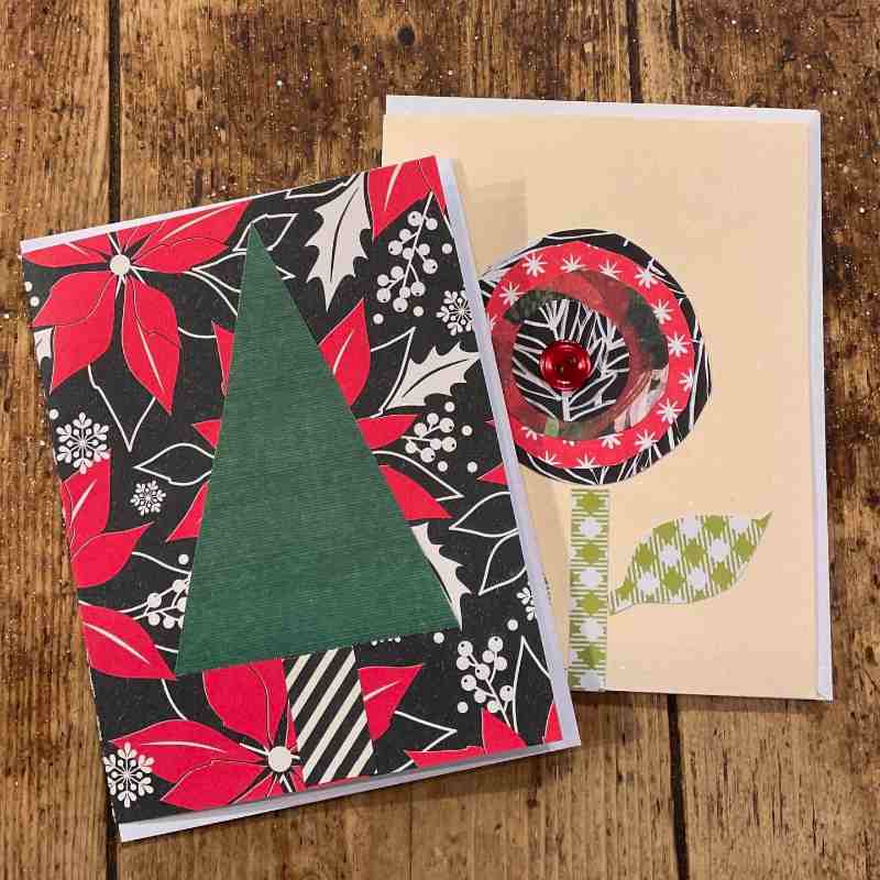 Two greeting cards on a wooden surface, one with a green tree and the other with a circular design.