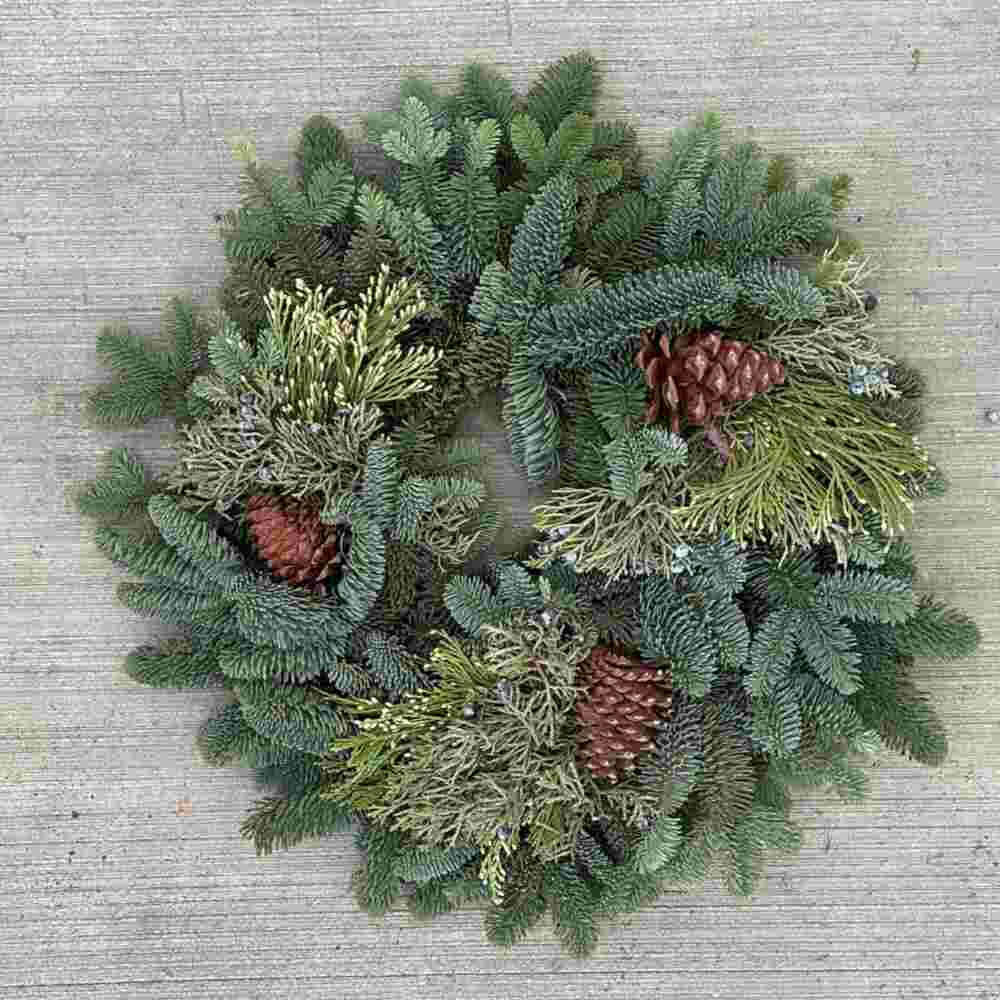 image of fresh wreath with several different types of evergreens, with three pine cones