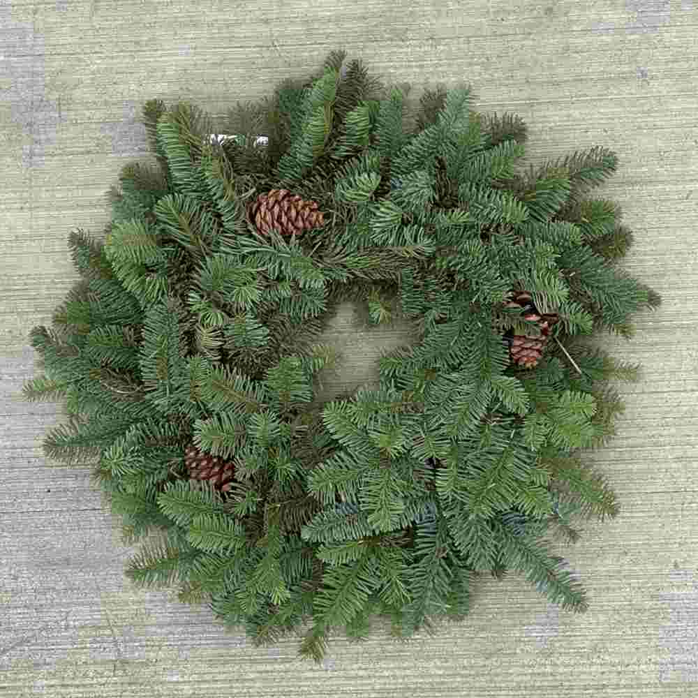 closeup image of a person's arm holding up a live green wreath decorated