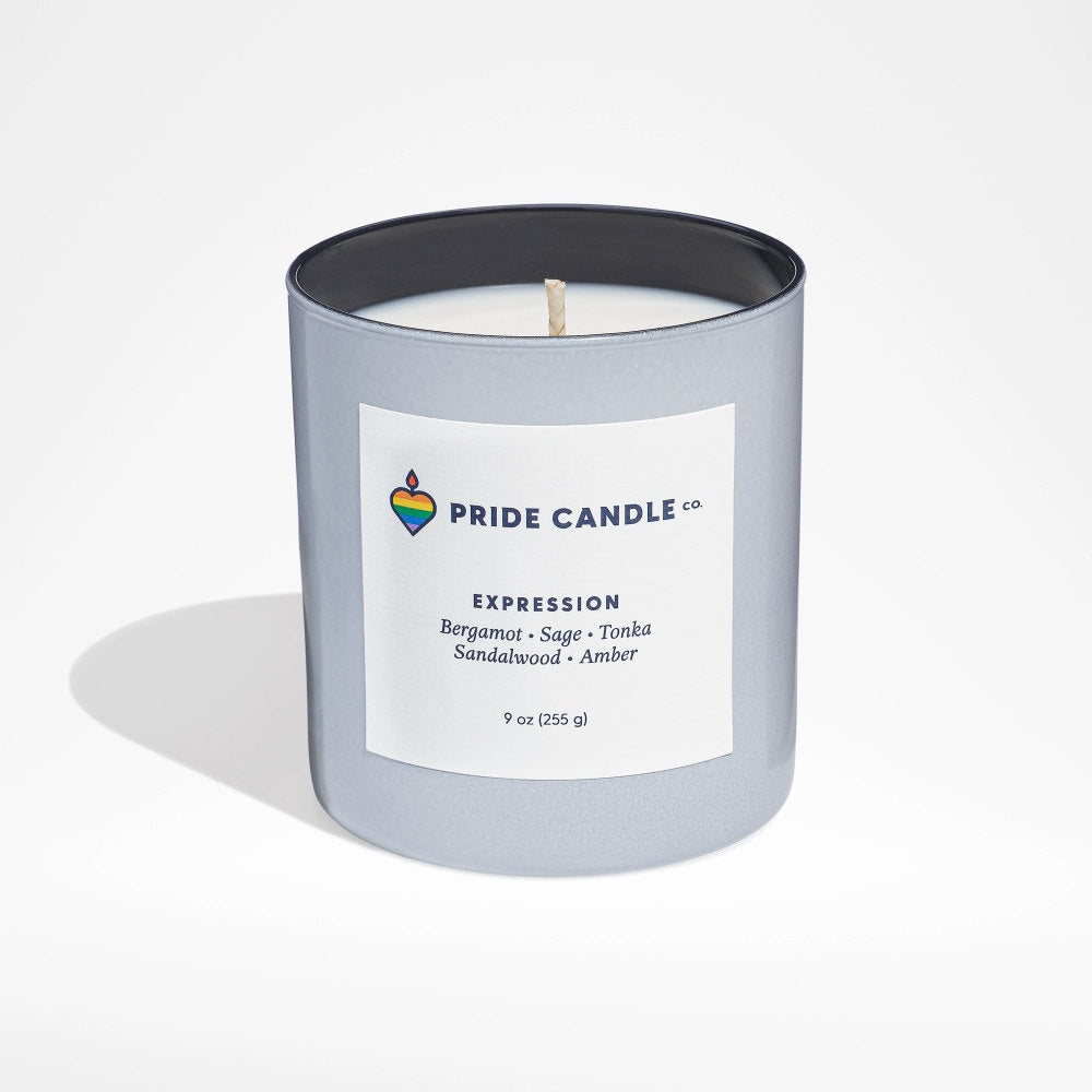 image of white candle in frosted white round glass jar, with dark grey interior.  White square label on outside of jar with Pride logo and candle info