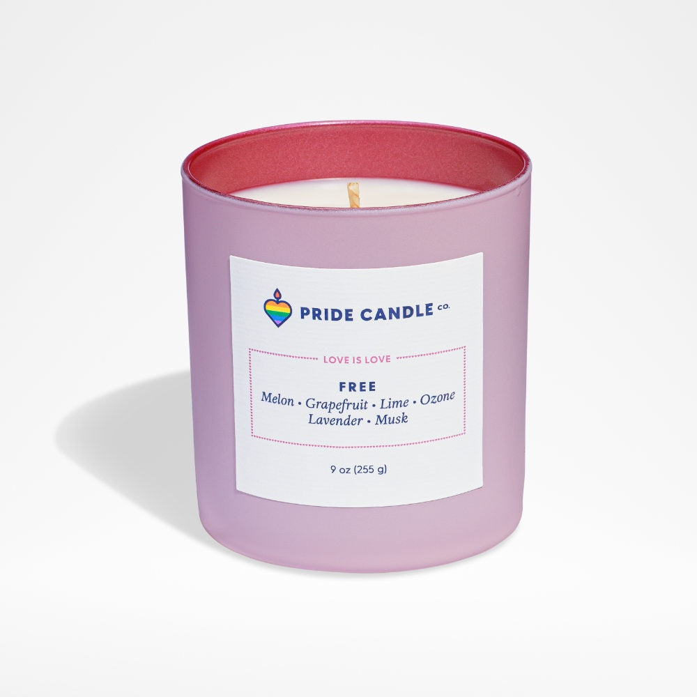 image of white candle in frosted pink round glass jar, with dark pink interior.  White square label on outside of jar with Pride logo and candle info