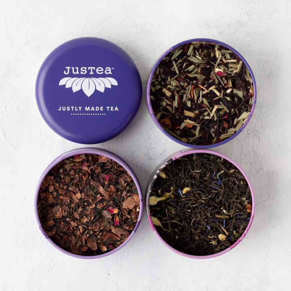 image from above of the three individual tea tins, showing the dried teas inside, along with the lid showing the Justea logo