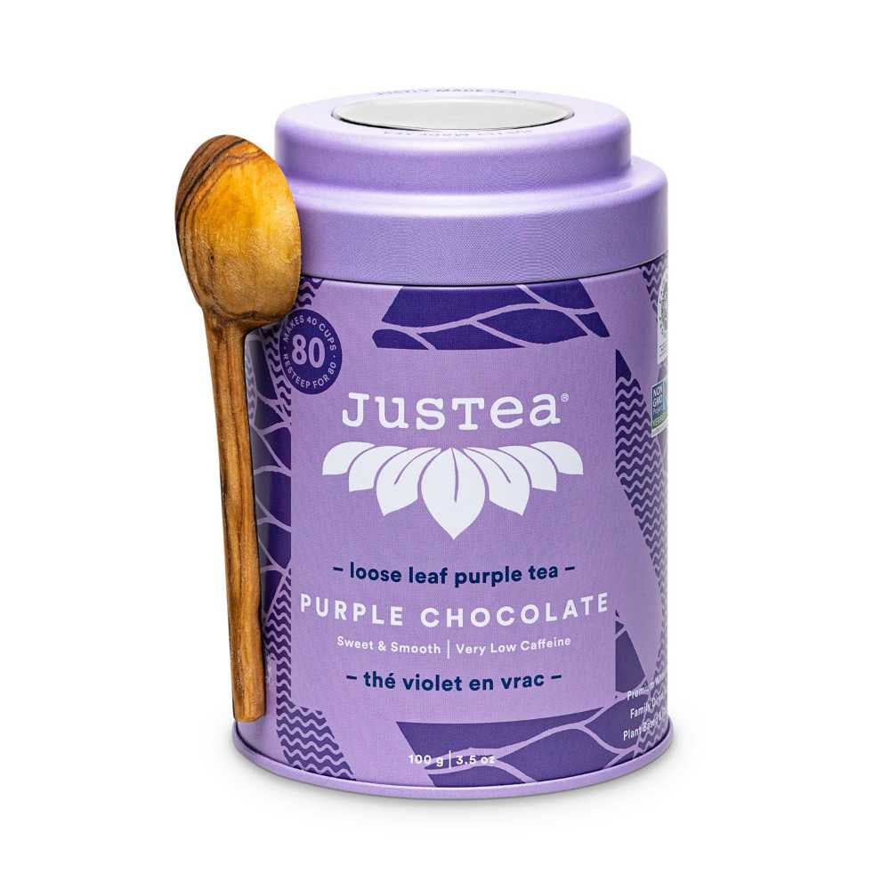  image of a round metal can in a purple color with a wooden carved spoon, with brand name and type of tea written in white 