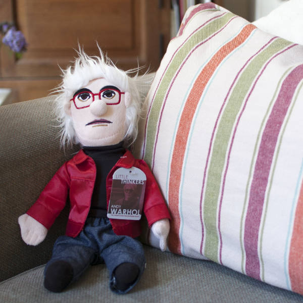 image of andy warhol doll sitting on a sofa in front of a multi color striped pillow