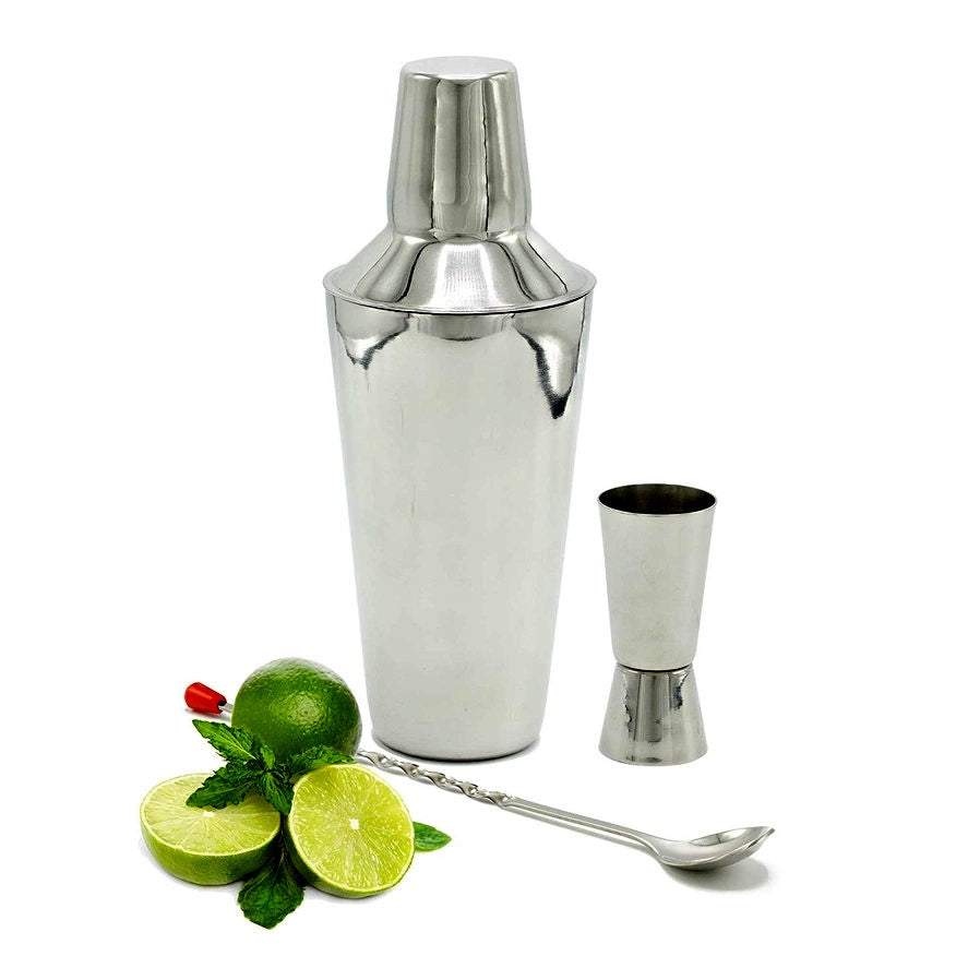 image of a stainless steel cocktail shaker, stainless jigger and matching long handled spoon.  limes and mint in front of the set