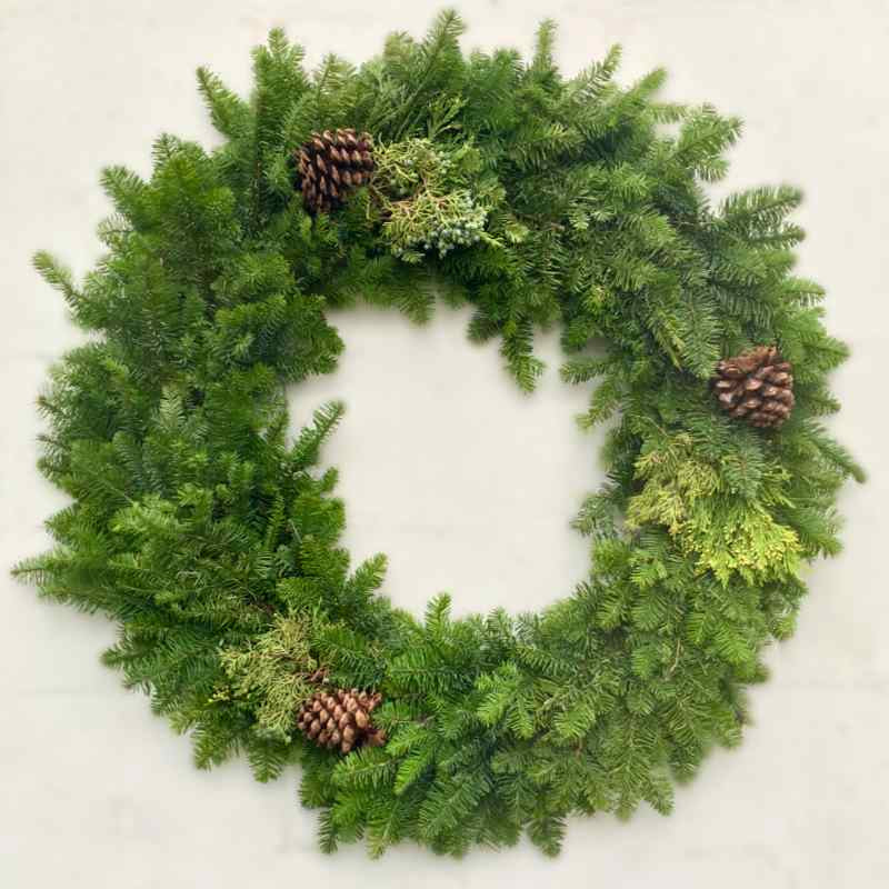 image of a large wreath with different types of fresh evergreens and three pine cones