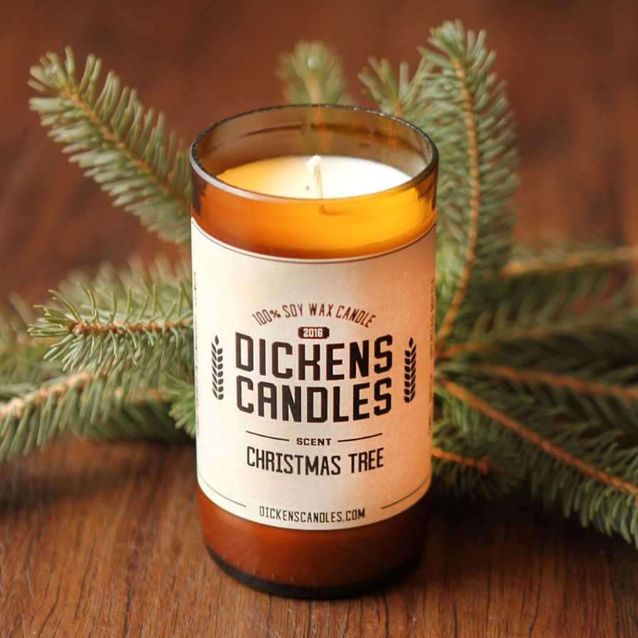 closeup image of candle in amber glass jar with pine branches in the background