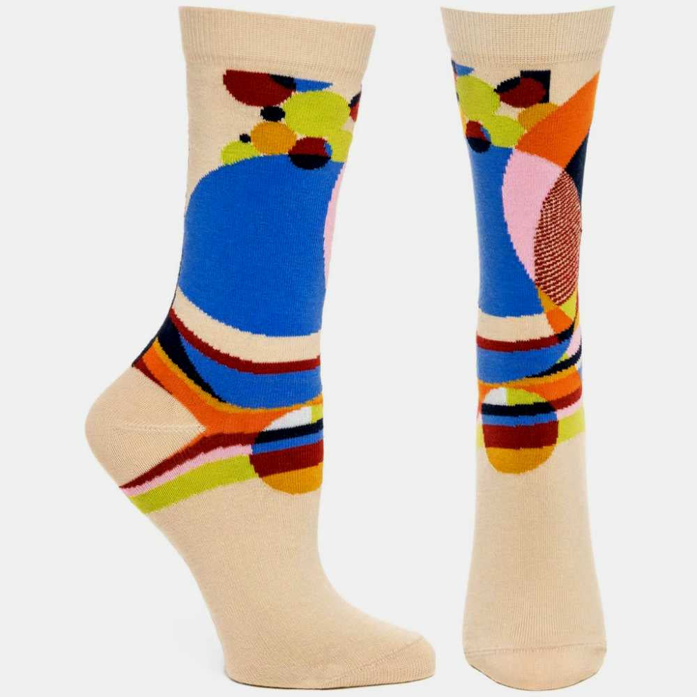 image of socks on feet.  sock on left is viewed from the side, sock on the right is viewed from the front.  Both socks are cream colored, with a large multi colored pattern of different sized circles intertwining.
