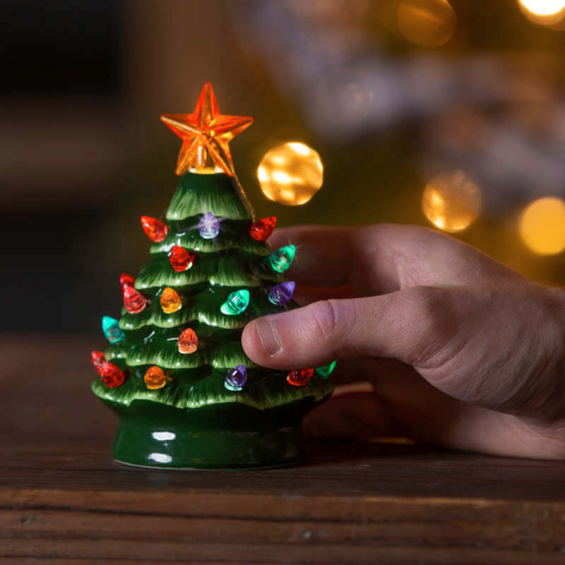 image of ceramic tree in variegated greens, with multi colored plastic lights and a yellow star on top.