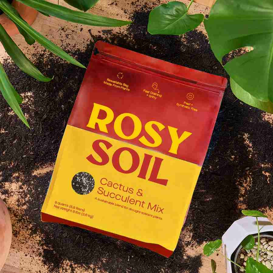 closeup image of bag of soil in red and yellow colors, sitting on a table scattered with soil