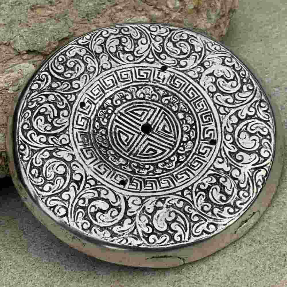 closeup image of round, intricately detailed tray. along with holes for incense sticks